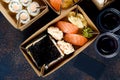 Tasty sushi rolls in disposable kraft paper boxes, sauces, chopsticks. Sushi for take away or delivery Royalty Free Stock Photo