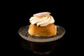 Swedish Semla in traditional glass plate isolated on black background with reflections, centered