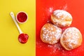 Tasty sweet sugary donuts with raspberry jam on bright yellow and red background