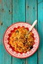 Tasty sweet vegetarian pumpkin pilaf with prunes in red plate on