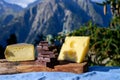 Tasty Swiss cheeses and dark pure chocolate, emmental, gruyere, appenzeller served outdoor with Alpine mountains peaks on Royalty Free Stock Photo