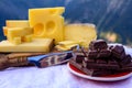 Tasty Swiss cheeses and dark pure chocolate, emmental, gruyere, appenzeller served outdoor with Alpine mountains peaks on Royalty Free Stock Photo