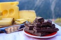 Tasty Swiss cheeses and dark pure chocolate, emmental, gruyere, appenzeller served outdoor with Alpine mountains peaks on Royalty Free Stock Photo