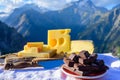 Tasty Swiss cheeses and dark pure chocolate, emmental, gruyere, appenzeller served outdoor with Alpine mountains peaks on Royalty Free Stock Photo