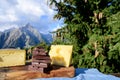 Tasty Swiss cheeses and dark pure chocolate, emmental, gruyere, appenzeller served outdoor with Alpine mountains peaks on Royalty Free Stock Photo