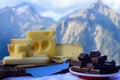 Tasty Swiss cheeses and dark pure chocolate, emmental, gruyere, appenzeller served outdoor with Alpine mountains peaks on Royalty Free Stock Photo