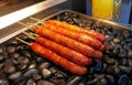 Tasty Taiwanese sausages on sticks on lava rock grill
