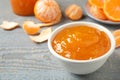 Tasty tangerine jam in bowl on grey wooden table. Space for text Royalty Free Stock Photo