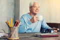 Cheerful pensioner drinking tea while sitting at the table