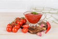 Tasty thick tomato ketchup in a glass gravy boat and ripe red cherry tomatoes, garlic and hot pepper pod on a white wood kitchen Royalty Free Stock Photo