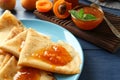 Tasty thin pancakes with apricot jam on plate