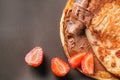 Tasty thin pancakes with chocolate spread and strawberries on dark background, closeup Royalty Free Stock Photo