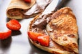 Tasty thin pancakes with chocolate spread and strawberries on plate, closeup Royalty Free Stock Photo