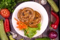 Tasty thin sausages with carrots and lettuce in a plate on a wooden table Royalty Free Stock Photo