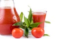 Tasty tomato juice in jug under water drops, glass juice, greens, two raw tomatoes isolated white background Royalty Free Stock Photo