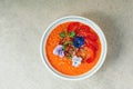 Tasty tomatoe soup in white bowl, decorated with little flowers, red bell pepper, hempseed and mint. Delicious meal. Vegetrian
