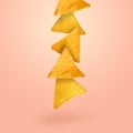 Tasty tortilla chips falling on light coral background Royalty Free Stock Photo