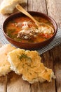 Tasty traditional beef and rice kharcho soup with spices and vegetables served with pita bread close-up. vertical