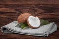 Tasty tropical coconuts with green leaves on a gray fabric on a wooden table. Exotic coconuts with green leaves. Healthy fruit.