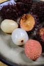 Tasty tropical exotic fruits, ripe fresh peeled and unpeeled lychee and hairy rambutan southeast Asian fruits rambutan southeast