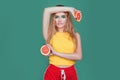 Tasty tropical fruits! Attractive sexual woman in bright sport clothes holding fresh juicy grapefruit or orange near face on isola Royalty Free Stock Photo