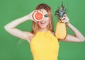 Tasty tropical fruits! Attractive sexual woman in bright sport clothes holding fresh juicy grapefruit and pineapple near face on i Royalty Free Stock Photo