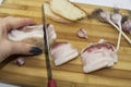 Tasty Ukrainian traditional food concept. A hand with knife cutting the salo on pieces. Raw bacon with bread and garlic being on Royalty Free Stock Photo