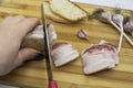 Tasty Ukrainian traditional food concept. A hand with knife cutting the salo on pieces. Raw bacon with bread and garlic being on Royalty Free Stock Photo