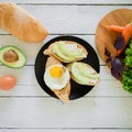 Tasty vegan breakfast. Sandwiches with avocado, eggs and bread on a dark plate on rustic background. Royalty Free Stock Photo