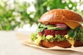 Tasty vegetarian burger with beet cutlet on table against blurred background.