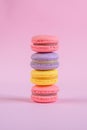 Tasty violet, pink and yellow french macaron cakes on pink background.