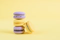 Tasty violet and yellow french macaron cakes on yellow background.