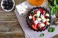 Tasty  vitamin salad with fresh vegetables, goat cheese, black olives, basil sauce on a white plate on a wooden background. Top Royalty Free Stock Photo