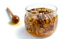 Tasty walnut with honey in a glass jar on a white isolated background. Nearby lies a spoon with dripping honey Royalty Free Stock Photo