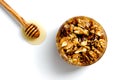 Tasty walnut with honey in a glass jar on a white background. Nearby lies a spoon with dripping honey. View from above