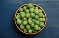 Tasty wasabi coated peanuts in bowl on blue wooden table, top view Royalty Free Stock Photo