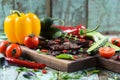 Tasty well done steak on oak board served with chili, bell pepper, cucumbers, tomatoes and greens Royalty Free Stock Photo