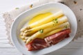 Tasty white asparagus with hollandaise sauce and ham close-up on