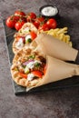 Tasty wrapped greek chicken gyros with vegetables, french fries and tzatziki sauce closeup on the board. Vertical Royalty Free Stock Photo