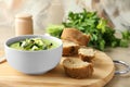 Tasty zucchini soup in bowl with bread on wooden board