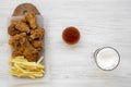 Tasy fast food: fried chicken legs, spicy wings, French fries and chicken tenders with sour-sweet sauce and cold beer over white Royalty Free Stock Photo