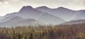 Tatra Mountains in the cold autumn morning covered by mist - colourful forest in the foreground