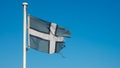 Tattered Devon county flag flies against a blue sky near Teignmouth Beach in Devon, UK Royalty Free Stock Photo
