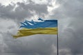 Tattered shabby Ukraine flag on gray cloudy