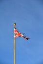A weatherbeaten tattered UK Union Flag against a bright blue sky Royalty Free Stock Photo