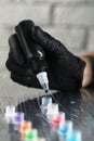 Tattoo artist dripping black tattoo ink into cap on table, closeup