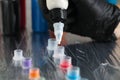 Tattoo artist dripping white tattoo ink into cap on table, closeup