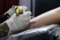 A tattoo artist fills a drawing on a man`s hand with a typewriter. The concept of overcoming pain, courage, creativity and