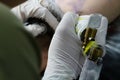 A tattoo artist fills a drawing on a man`s hand with a typewriter. The concept of overcoming pain, courage, creativity and