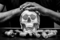 Tattoo artist folded hands on plaster skull surrounded by typewriter ink, black and white photo